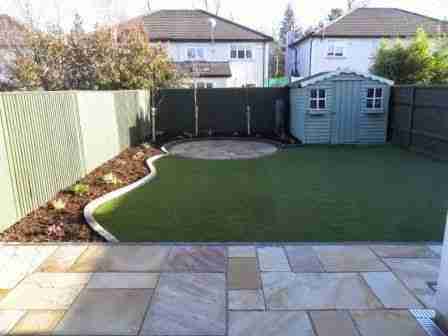 Newly completed garden makeover with sandstone patio areas & raised beds and synthetic lawn.