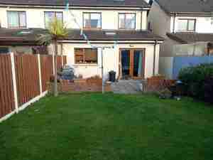 Unappealing garden space with lawn and tired paving and little soft planting